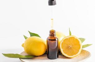 un producto natural orgánico para el cuidado de la piel del rostro a base de aceite esencial de limón en una botella transparente y una pipeta. Fondo blanco. vista frontal. foto