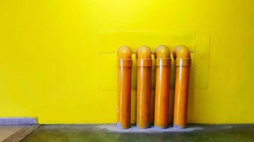 Four yellow water pipeline on yellow concrete wall for background with copy space. Oil pipe installed on floor. photo