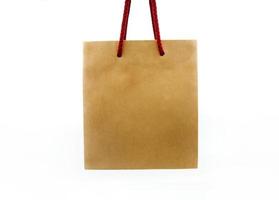 bolsa de compras marrón con cuerda roja aislada en fondo blanco con trazado de recorte o selección. contenedor de papel, material natural y objeto de reciclaje. foto