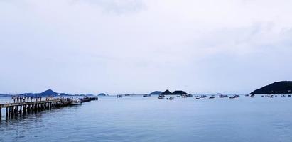 puente largo entre el mar o el océano con muchos barcos y fondo de cielo blanco en el puerto de phuket, tailandia. vista al mar con montaña y natural con foto