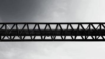 vista inferior de la bandeja de cables eléctricos o de comunicación de acero inoxidable con fondo de cielo con espacio de copia en tono blanco y negro. puente de hierro cruzado al aire en estilo monocromo. foto