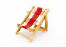 pequeña cubierta de madera o silla de playa aislada sobre fondo blanco. objeto de juguete foto