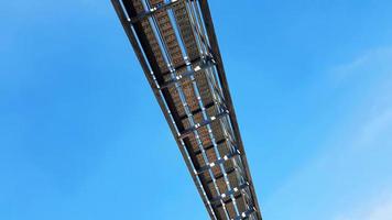Bottom view of stainless steel electrical or communication cable tray with clear blue sky background with copy space. Iron bridge cross to air or heaven and industrial and installed system concept. photo