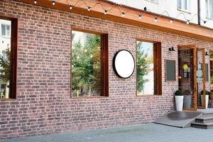 Cafe exterior in loft style with red brick wall, white round logo for mockup design photo