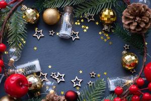 Festive frame with a place for Christmas and New Year's theme text. Sequins, stars, garland, cones, balls on a black stone background of slate. Copyspace, greeting card photo