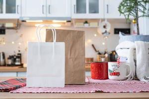 Food delivery service containers on table white scandi festive kitchen in christmas decor. Eve New year, saving time, too lazy to cook, hot order, disposable plastic box in fairy light. mock up photo