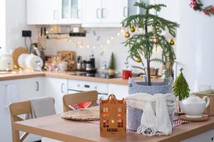 Key to the house on cozy home with Christmas decor on table of festive kitchen. Gift for New Year. Building, design, project, moving to new house, mortgage, rent and purchase real estate photo