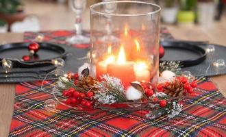 Festive table set in the living room for Christmas and New year in loft style. Christmas tree, black plates and forks, woven napkins, trendy tableware, cozy interior of the house photo