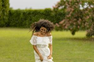 Joyful young woman caught by the summer rain in the park