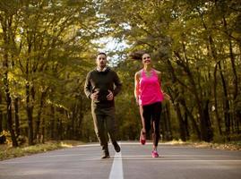 Athletic couple running together on the forest trail photo