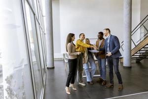 miembros del equipo creativo dándose la mano mientras trabajan en la oficina moderna foto