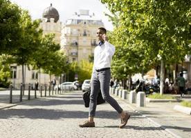 Young African American businessman using a mobile phone while crossing a street photo