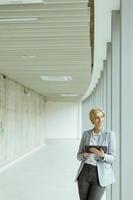 Businesswoman using digital tablet on modern office hallway photo
