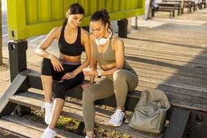 Young women in sportswear looking at mobile phone after exercise training