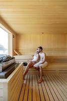 Young couple relaxing in the sauna and watching winter forest through the window photo