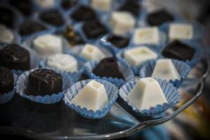 Assorted white and dark chocolate pralines arranged on a glass plate photo