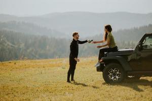 Smiling couple preparing hiking adventure with backpacks by terrain vehicle photo