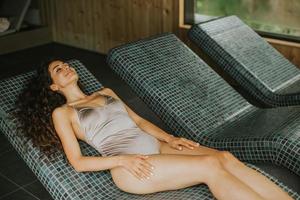 Young woman relaxing on the tepidarium bed in the spa photo