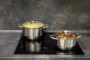 pots with cutlets and boiled potatoes on the induction stove photo