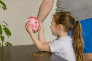 dad gives little daughter a piggy bank photo