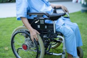 Paciente asiático mayor o anciano en silla de ruedas eléctrica con control remoto en la sala del hospital de enfermería, concepto médico fuerte y saludable foto