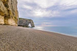 vista panorámica de los acantilados de etretat en normandía francia con playa de guijarros contra el cielo dramático foto