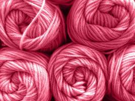 Wool yarn skeins are folded in stacks, close-up texture. Photo toned in color of the year 2023 viva magenta.