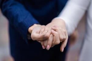 manos de la novia y el novio con anillos. novia y novio en un café. mesa de ramo de boda. la novia y el novio se dan la mano. anillos de boda. pareja amorosa en un café. té caliente para los amantes foto