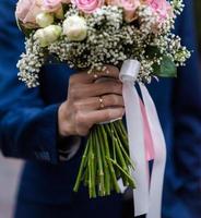 la novia con un vestido de novia blanco sostiene un ramo de flores blancas: peonías, rosas. boda. la novia y el novio. delicado ramo de bienvenida. hermosa decoración de bodas con hojas