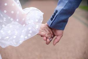 hands of bride and groom with rings. bride and groom in a cafe. wedding bouquet table. bride and groom hold each other's hands. Wedding rings. Loving couple in a cafe. hot tea for lovers photo