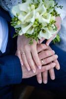 hands of bride and groom with rings. bride and groom in a cafe. wedding bouquet table. bride and groom hold each other's hands. Wedding rings. Loving couple in a cafe. hot tea for lovers photo