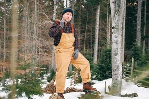 retrato de un hombre leñador con un hacha en las manos sobre un fondo de bosque y árboles foto