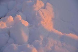 inviernos de nieve rosa a la luz del sol poniente. nieve esponjosa de invierno rosa y azul en invierno. un ventisquero en los rayos del sol poniente. foto