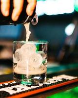 putting beer in the glass with ice cube photo