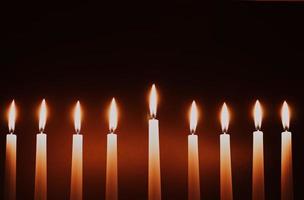 Hanukkah candles. Traditional candelabrum with burning candles on black background. Celebrating religious Jewish holiday. photo