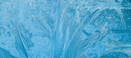 Frosty patterns on glass. Christmas background. Ice on winter window. Abstract crystals close up. photo
