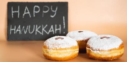 Happy Hanukkah. Traditional Jewish dessert Sufganiyot. Celebrating Judaism holiday. Donuts with jam and sugar powder. photo