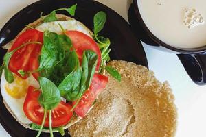 home breakfast meal - fried eggs with tomato and fresh spinach on pita, tea with milk photo