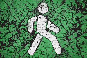 Pedestrian icon on green. Cracked paint on asphalt. Go green and pedestrian priority concept photo