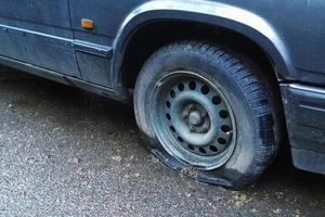 old car with flat tyre on the street, closeup photo