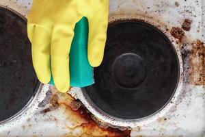 hand in household glove cleaning grease and dirt from kitchen stove photo