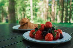 un croissant y un plato de fresas en una autocaravana. elementos esenciales para acampar van life foto