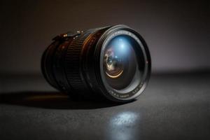 Camera lens sits on a dark table under a spotlight tech review photo