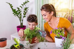 mamá y niño riegan las plantas juntos, la pequeña asistente de jardinero de mamá, cuida de los niños y las flores. chico lindo regando de la regadera, cuidando árboles y plantas, niño mojado foto