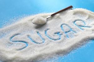 azúcar en cuchara y fondo azul, azúcar blanco para alimentos y dulces dulces de postre montón de azúcar dulce granulado cristalino foto