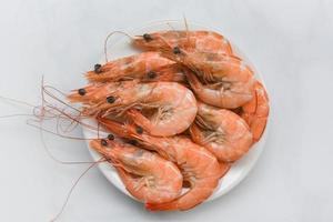 fresh shrimp on white plate - cooking seafood shrimps prawns served on a food table background photo