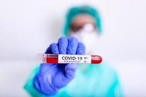 covid-19, virus de la corona o nueva enfermedad epidémica de coronavirus con médico o técnico de laboratorio científico en equipo de protección personal de ppe que realiza pruebas de tubos de sangre en el laboratorio del hospital foto