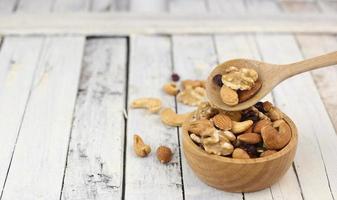 Many healthy nuts on wooden spoon against white wood photo