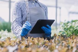 Futuristic businessman farms vegetables and crops using modern AI technology using mobile phones, temperature and humidity sensors, water tracking, climate control, holographic data data icons. photo
