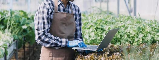 Futuristic businessman farms vegetables and crops using modern AI technology using mobile phones, temperature and humidity sensors, water tracking, climate control, holographic data data icons. photo